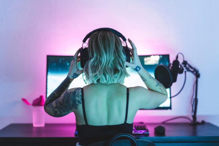 Image of a woman putting on headphones in front of a computer screen and microphone.